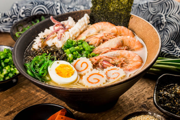 A bowl of ramen filled with shrimp, sliced fish cake, boiled egg, seaweed, and green onions.