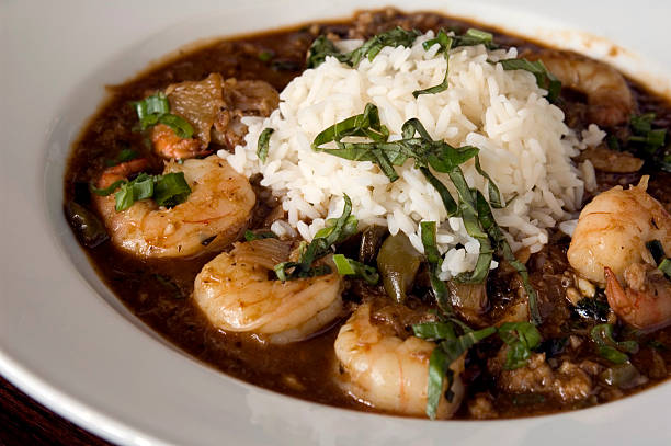 A bowl of shrimp with rice and garnished with fresh herbs.