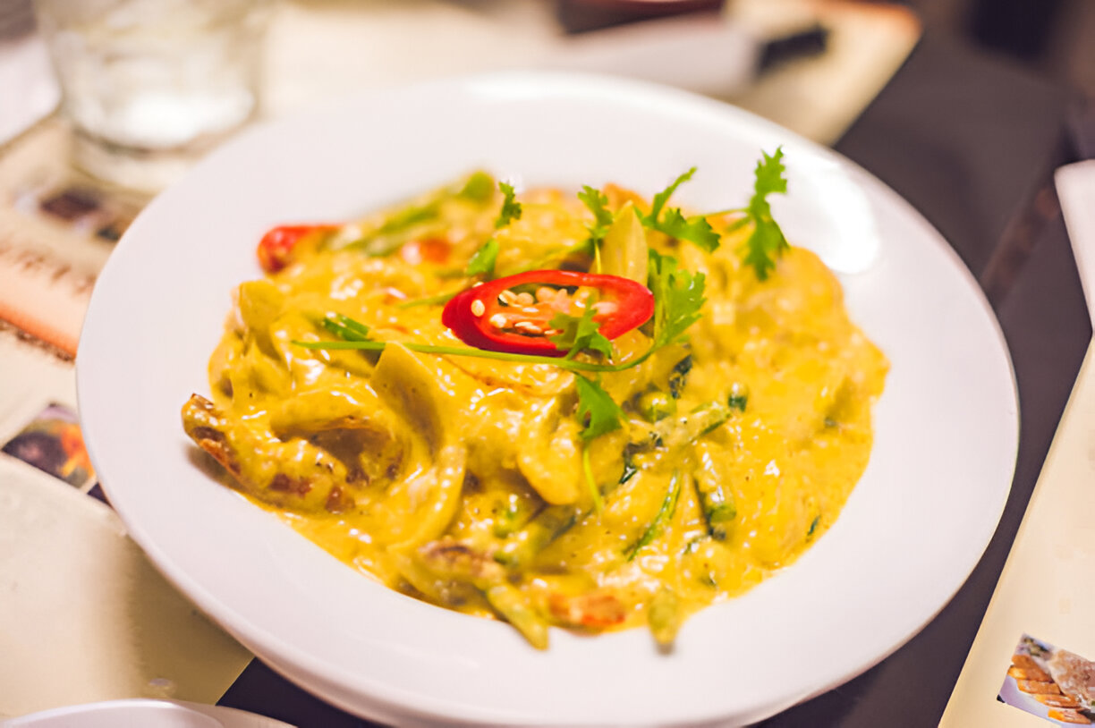 A delicious plate of creamy pasta topped with green herbs and red chili slices.