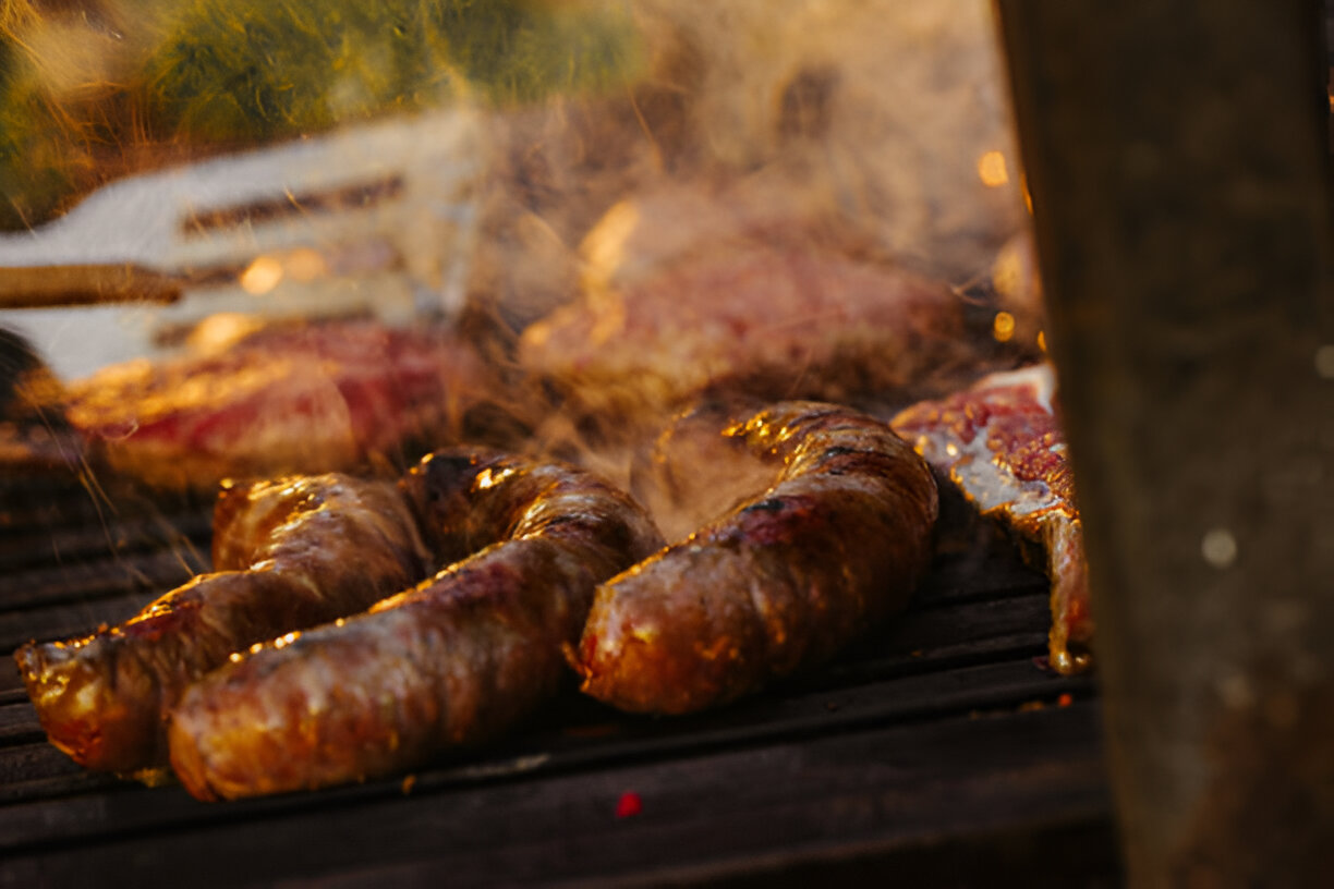 Close-up of sausages grilling on a barbecue with smoky background