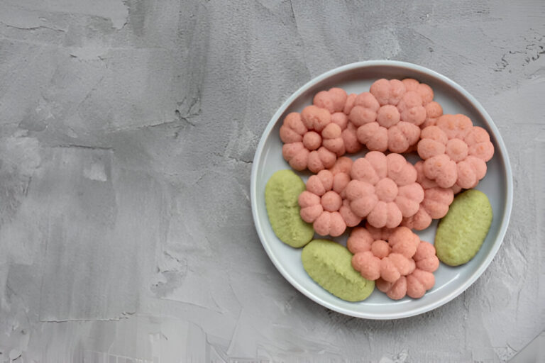 A plate filled with pink flower-shaped snacks and green snacks.