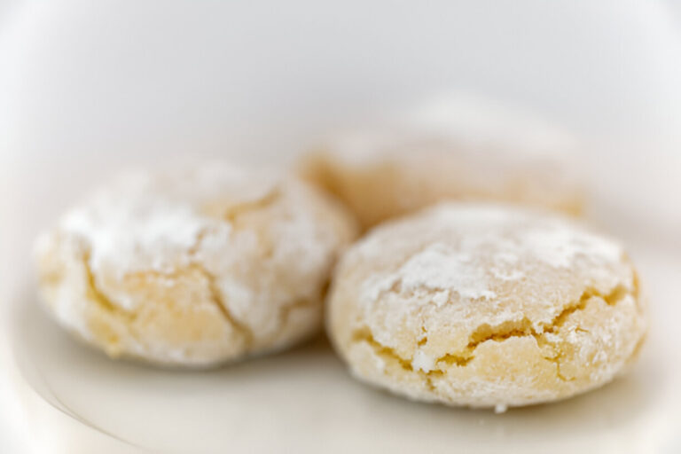 Close-up of three powdered sugar-coated cookies on a white plate