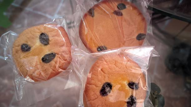 Three smiley face cookies wrapped in plastic on a table.