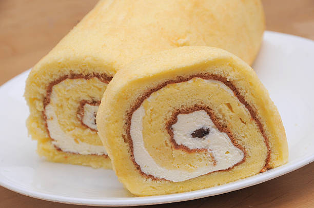 Close-up of a sliced roll cake with cream filling on a white plate