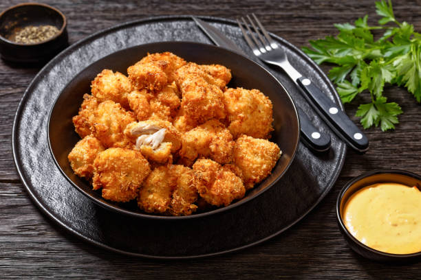 A bowl of golden, crispy fried chicken bites served with dipping sauce and garnished with parsley.