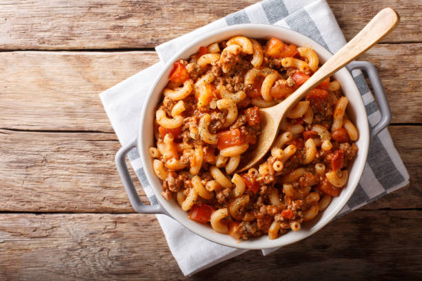 A bowl of macaroni with meat and tomato sauce on a wooden table