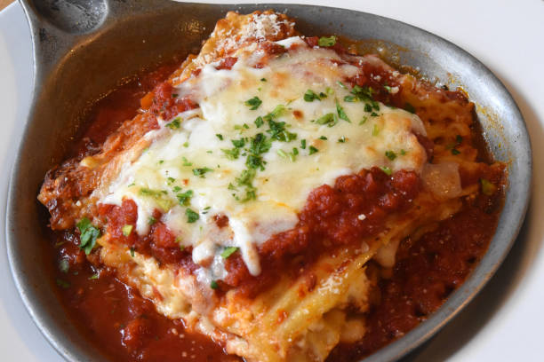 A serving of lasagna topped with cheese and marinara sauce in a metal dish