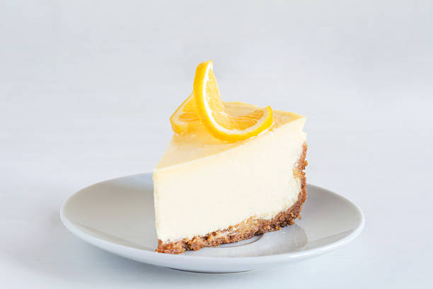 A slice of lemon cheesecake on a gray plate with a lemon slice on top