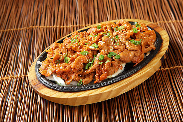 Sizzling plate of chicken dish topped with sesame seeds and green onions