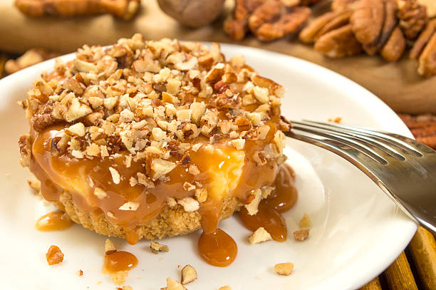 A delicious dessert topped with crushed pecans and drizzled with caramel sauce on a white plate.