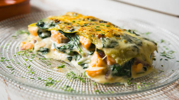 A delicious serving of spinach lasagna topped with golden cheese on a glass plate.