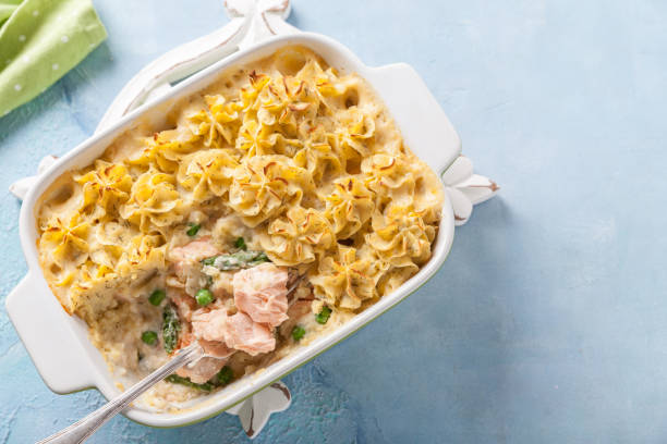 Creamy casserole with noodles, salmon, and vegetables baked in a white dish