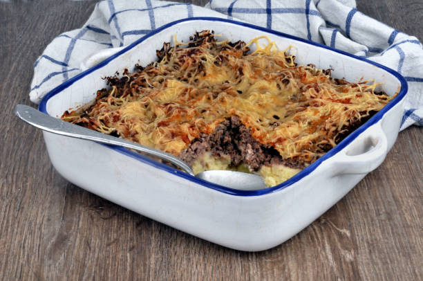 A baked casserole dish filled with a golden-brown topping, showing layers of ground meat and other ingredients.