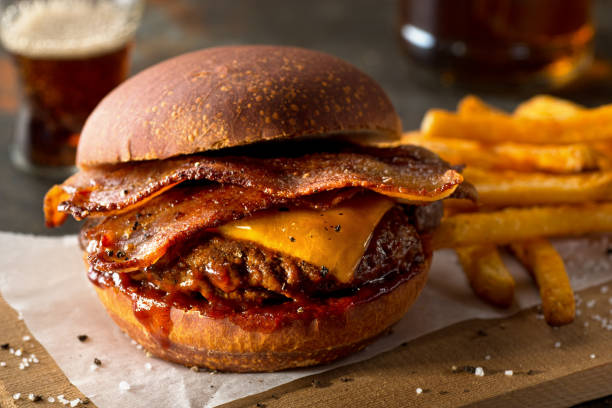 A delicious bacon cheeseburger with crispy bacon, cheddar cheese, and barbecue sauce, served with golden French fries.