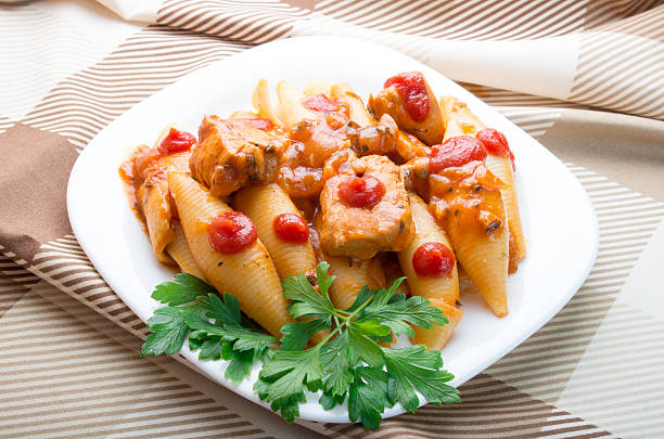 A plate of pasta shells filled with meat, topped with red sauce and garnished with fresh parsley.