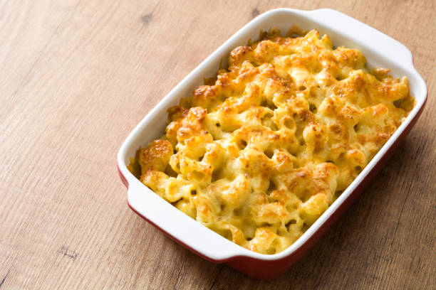 A delicious baked macaroni and cheese in a white and red dish on a wooden table.