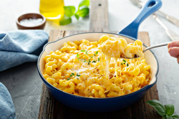 A serving of creamy macaroni and cheese in a blue dish, with melted cheese stretching on a fork.