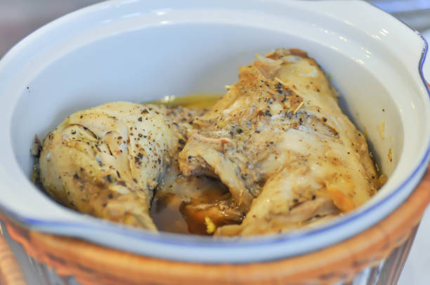 Cooked chicken legs in a serving dish with herbs and spices.