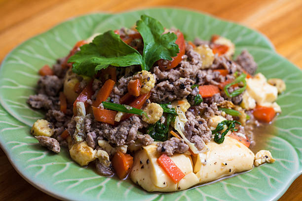 A plate of cooked ground meat with tofu and vegetables garnished with cilantro.