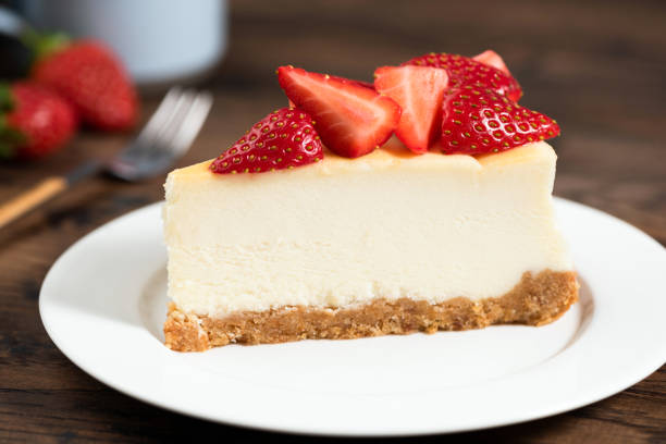 A slice of cheesecake topped with fresh strawberries on a white plate