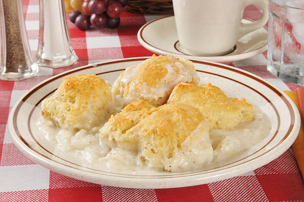 A plate of biscuits and creamy gravy served on a checkered tablecloth.