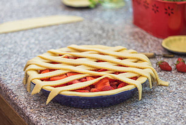 A freshly prepared strawberry pie with a lattice crust resting on a kitchen countertop.