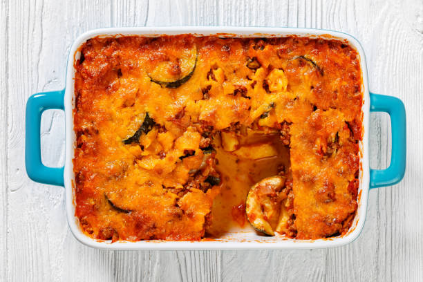 Baked casserole dish with a golden top and a serving removed, showcasing ingredients like zucchini and a hearty filling.