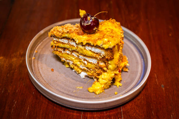 A slice of layered cake topped with a cherry, sitting on a gray plate.