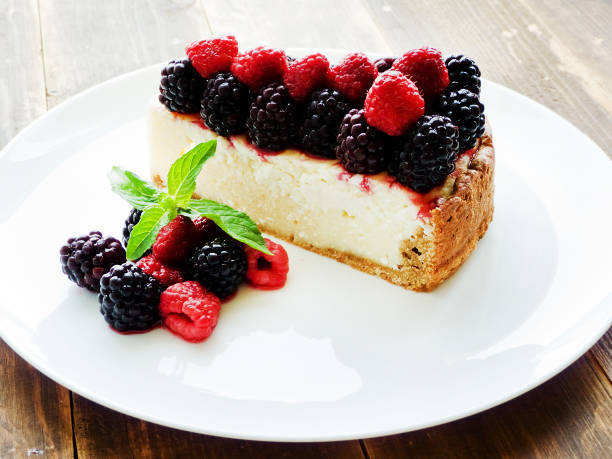 A slice of cheesecake topped with fresh raspberries and blackberries on a white plate