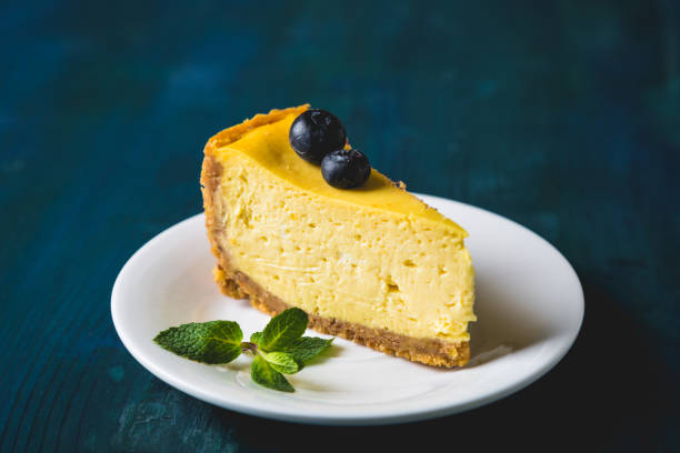 A slice of cheesecake topped with blueberries and mint leaves on a white plate