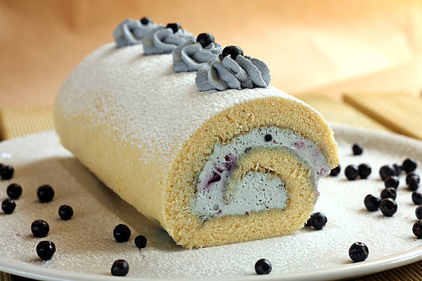 A delicious rolled cake filled with cream and decorated with blue cream and blueberries.