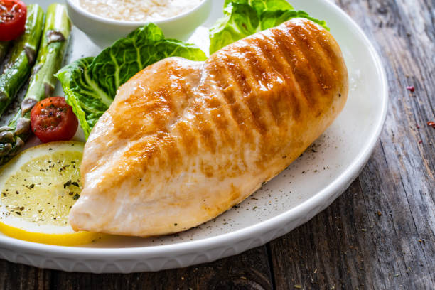 Grilled chicken breast with vegetables on a white plate