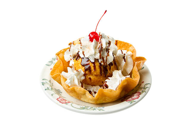 A delicious ice cream dessert topped with whipped cream, chocolate drizzle, and a cherry, served in a crispy waffle bowl.