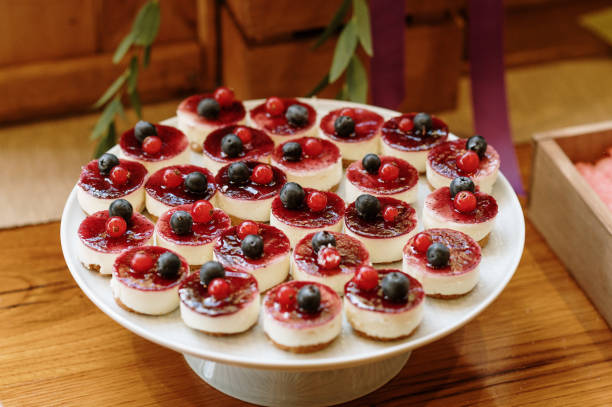 A plate of mini cheesecakes topped with red and blue berries.