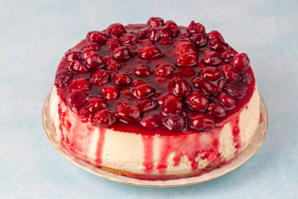 A delicious cheesecake topped with a glossy cherry glaze and whole cherries, placed on a decorative plate.