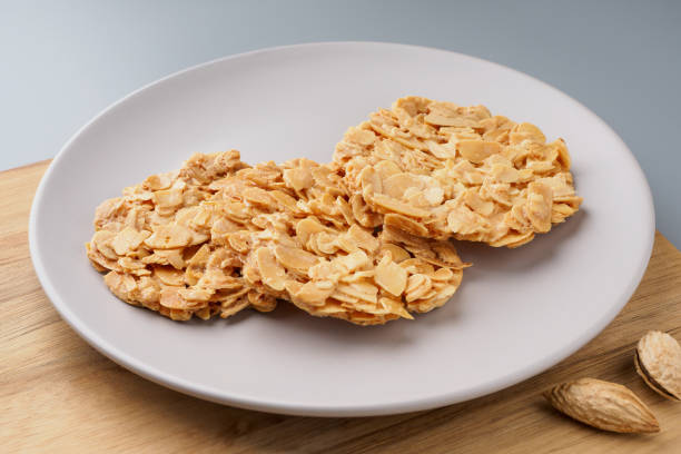 Three almond confectionary pieces on a white plate with whole almonds on the side.