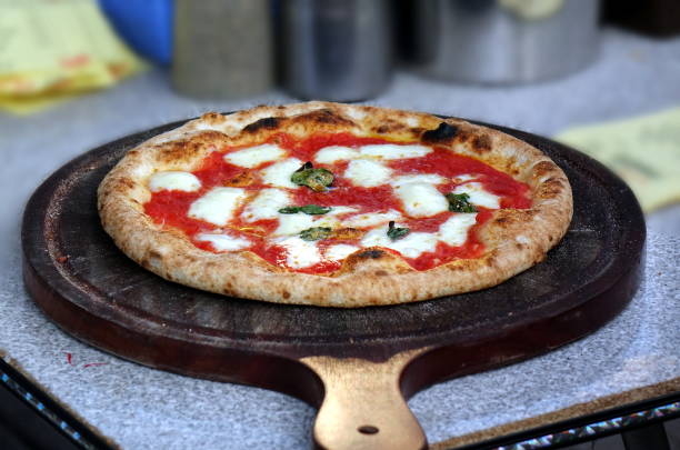 A freshly baked Margherita pizza on a wooden pizza peel.