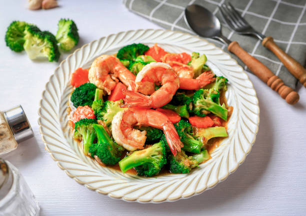 A plate of shrimp and broccoli stir-fry garnished with colorful vegetables.