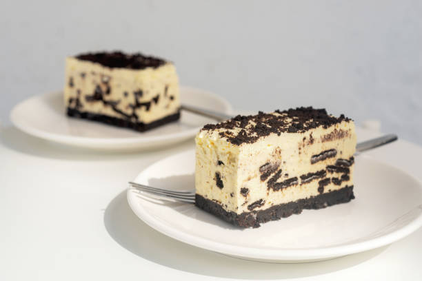 Two slices of Oreo cheesecake on white plates with forks