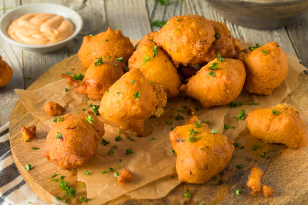 A plate of golden-brown fritters garnished with green herbs, served on parchment paper.