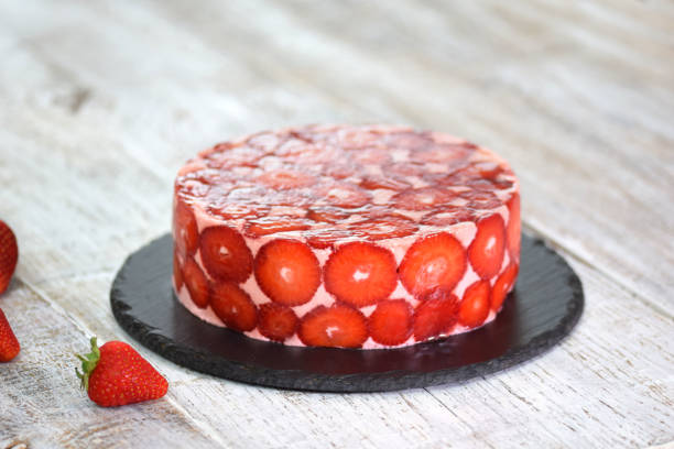 A beautifully presented strawberry cake on a black slate plate.