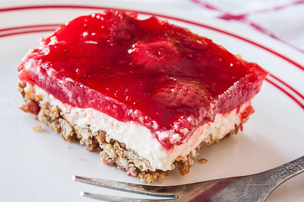 A slice of strawberry dessert on a white plate with a silver fork.