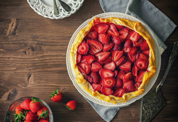 A delicious strawberry tart topped with fresh strawberries, served on a decorative plate.