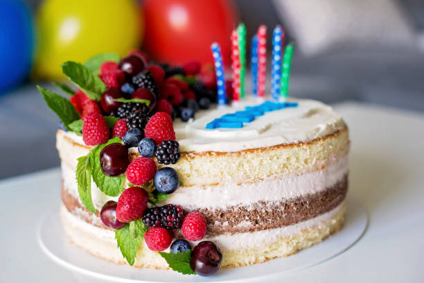 A delicious layered cake topped with fresh berries and birthday candles.