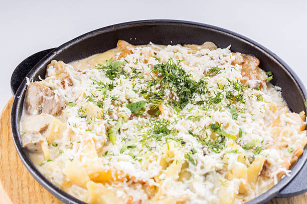 A delicious dish featuring pasta layered with creamy sauce and topped with melted cheese and fresh herbs in a black skillet.