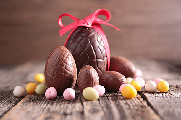 Chocolate Easter eggs with a red ribbon on a wooden surface.