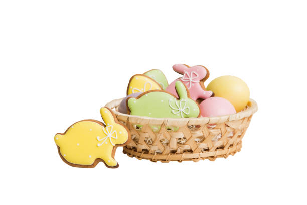 A woven basket filled with pastel-colored rabbit-shaped cookies and decorative eggs.