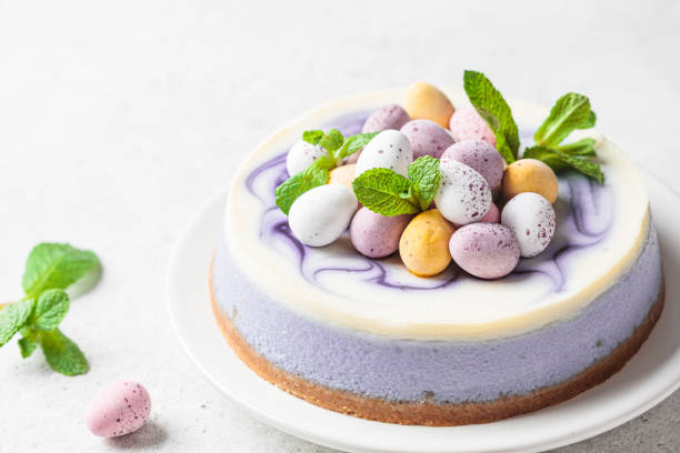 A visually appealing cake topped with pastel-colored eggs and fresh mint leaves on a white plate.