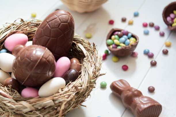 A nest filled with chocolate eggs and colorful candy on a wooden surface.