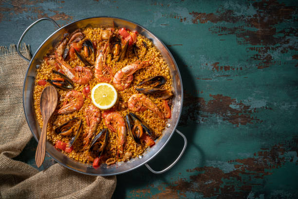 A vibrant seafood paella with shrimp and mussels garnished with a lemon slice, served in a traditional pan.